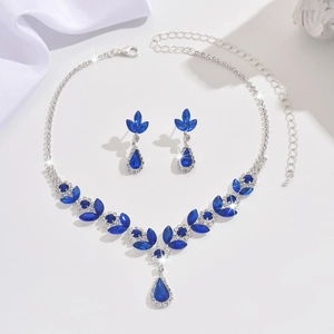 Macro detail of silver necklace and earrings set with deep blue pear-cut crystals