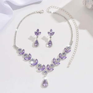 Detail view of purple crystal bridal jewelry set with necklace and earrings on silk background