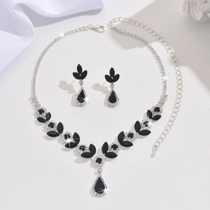 Detailed view of silver necklace and earrings set with black teardrop crystal stones