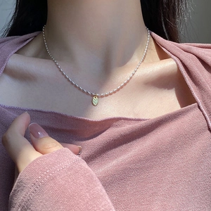 Nahaufnahme des goldenen LOVE-Anhängers an einer silbernen Reiskornkette am Model