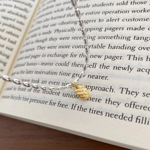 Minimalistische silberne Perlenkette mit goldenem LOVE-Anhänger auf einem Buch