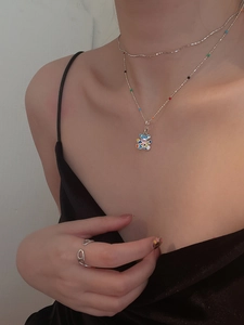 Detail of a silver rainbow enamel bear pendant necklace and ring on a female model