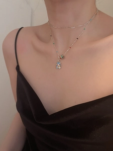 Close-up of double layer silver chain with a colorful enamel bear pendant on a model