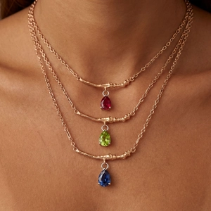 Rose gold layered necklace with branch textured bar and three pear-cut colored gemstones