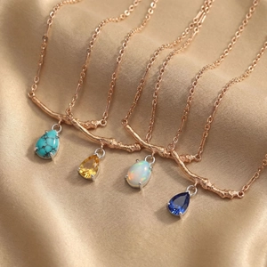 Rose gold pear-cut gemstone necklaces with branch design on champagne satin fabric