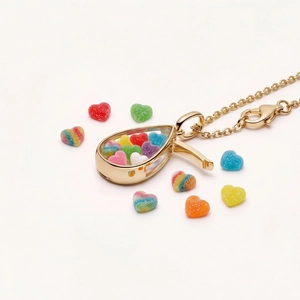 Collier médaillon doré en forme de goutte avec breloques cœur et fond blanc épuré