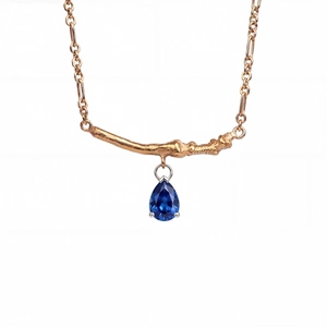 Detail of gold branch pendant with pear-cut blue zircon on a fine link chain