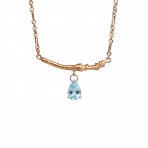 Detailed view of the gold-plated branch pendant featuring a pear-cut blue zircon stone
