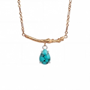 Detailed close-up of a gold branch necklace with a water-drop turquoise pendant