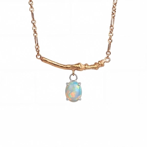 Macro detail of rose gold branch texture and oval fire opal pendant on necklace