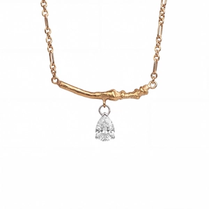 Close-up of gold branch-shaped pendant with a sparkling teardrop zircon stone