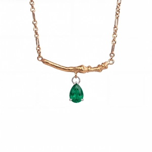 Detail of pear-cut emerald pendant with golden tree branch texture and fine cable chain