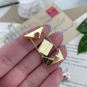 Detail view of gold envelope necklace showing hidden I Love You engraving and red heart
