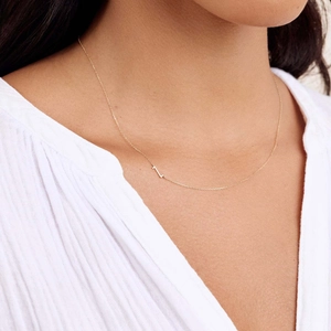 Detail of minimalist gold plated stainless steel necklace with side-set capital letter L