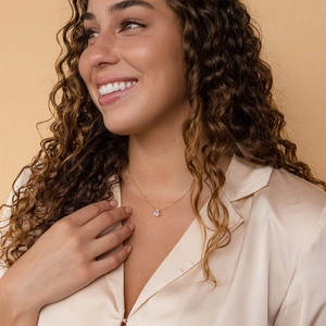 Detailed close-up of a pear-shaped zircon necklace in 18k gold plating on a model