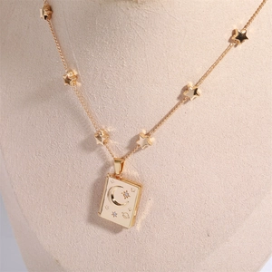 Detail of gold star and moon locket necklace on a beige mannequin bust