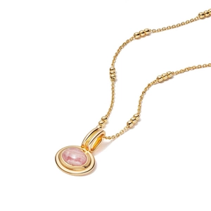 Detail of a pink gemstone oval pendant on a gold beaded chain with high polished finish