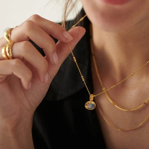 Detailed close-up of a layered gold necklace with an oval iridescent gemstone pendant