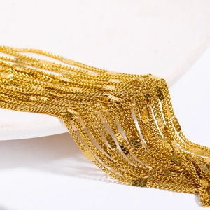 Detail of high-gloss gold layered chains on a white curved stand with metallic shine