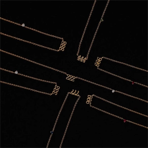 Radial display of gold angel number necklaces with crystal accents on black background
