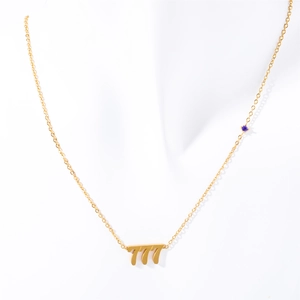 Golden stainless steel angel number 777 necklace with blue gem on white fabric