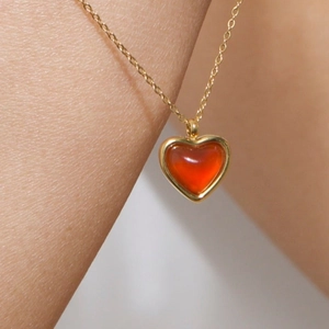 Detail einer roten Herz-Karneol-Halskette mit Goldkette an einem minimalistischen Hals