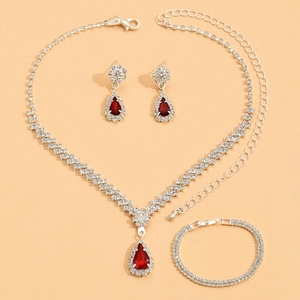 Detailed set of silver bridal jewelry with red teardrop gems and white crystals