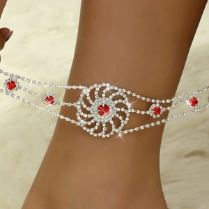 Détail d'une chevillère de mariée en strass avec gemme rouge et charm soleil sur tapis