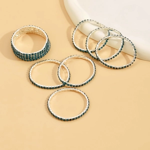 Detail of seven elastic silver bracelets with deep blue rhinestones on a ceramic plate
