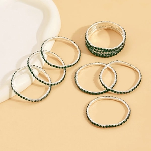 Detail of silver bangles set featuring emerald green square-cut zircons in claw setting