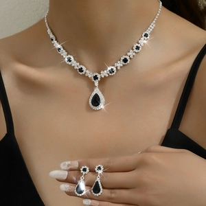 Detailed close-up of a pear-cut black gemstone necklace and earrings on a model