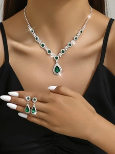Close-up of teardrop emerald crystal necklace and earrings set worn by a fashion model