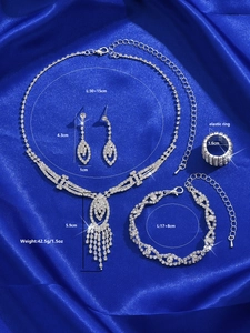 Detailed view of silver rhinestone jewelry set with tassel necklace on blue silk