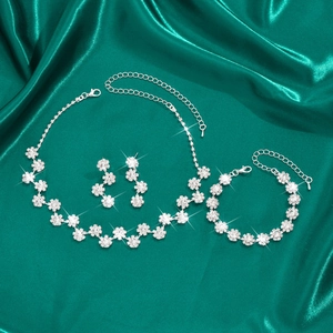 Makroaufnahme von silbernem Kristall-Blumenschmuckset mit Halskette und Ohrringen auf Seide