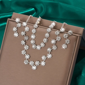 Makroaufnahme von silbernem Blumenschmuck-Set mit glitzernden Strasssteinen auf Seide
