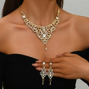 Detailed view of luxury gold necklace and drop earrings set with crystals on model