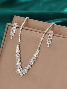 Close-up of sparkling bridal jewelry set with V-shaped rhinestone necklace and earrings
