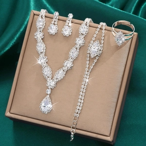 Detail shot of silver bridal jewelry set with teardrop zircons on green silk background