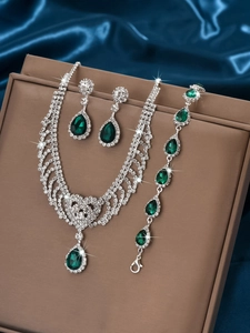 Detail of luxury emerald green pear-cut gemstones and silver crystal jewelry set