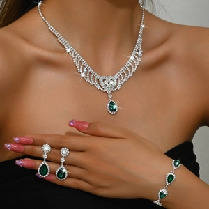 Detailed view of silver necklace and earrings with waterdrop green gemstones and diamonds