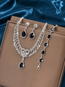 Elegant close-up of silver-tone jewelry set featuring black teardrop stones and crystals