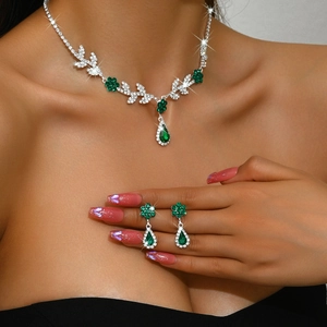 Gros plan d'un collier fleur en strass vert et boucles d'oreilles goutte