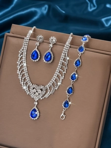 Close-up of luxury waterdrop necklace and earring set with blue stones on silk background