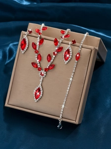 Macro detail of silver V-shaped bridal jewelry set with red gems on blue satin
