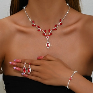 Detail view of a V-shaped necklace, teardrop earrings, and bracelet with red gemstones