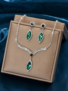 Close-up of elegant V-shape bridal jewelry set with emerald green crystals and rhinestones