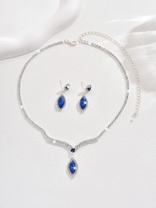Close-up of V-shaped silver necklace and earrings set with blue marquise crystals