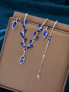 Detailed view of silver necklace and earrings set with deep blue crystal leaf patterns