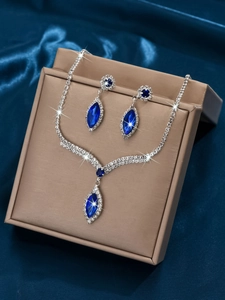 Close-up of bridal jewelry set with navy blue stones and rhinestones on silk background
