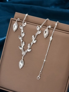 Detailed view of silver V-shaped bridal jewelry set with sparkling rhinestones on velvet